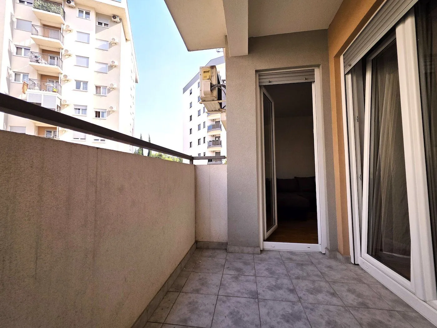 Covered balcony with tiled floor and view of neighbouring buildings.