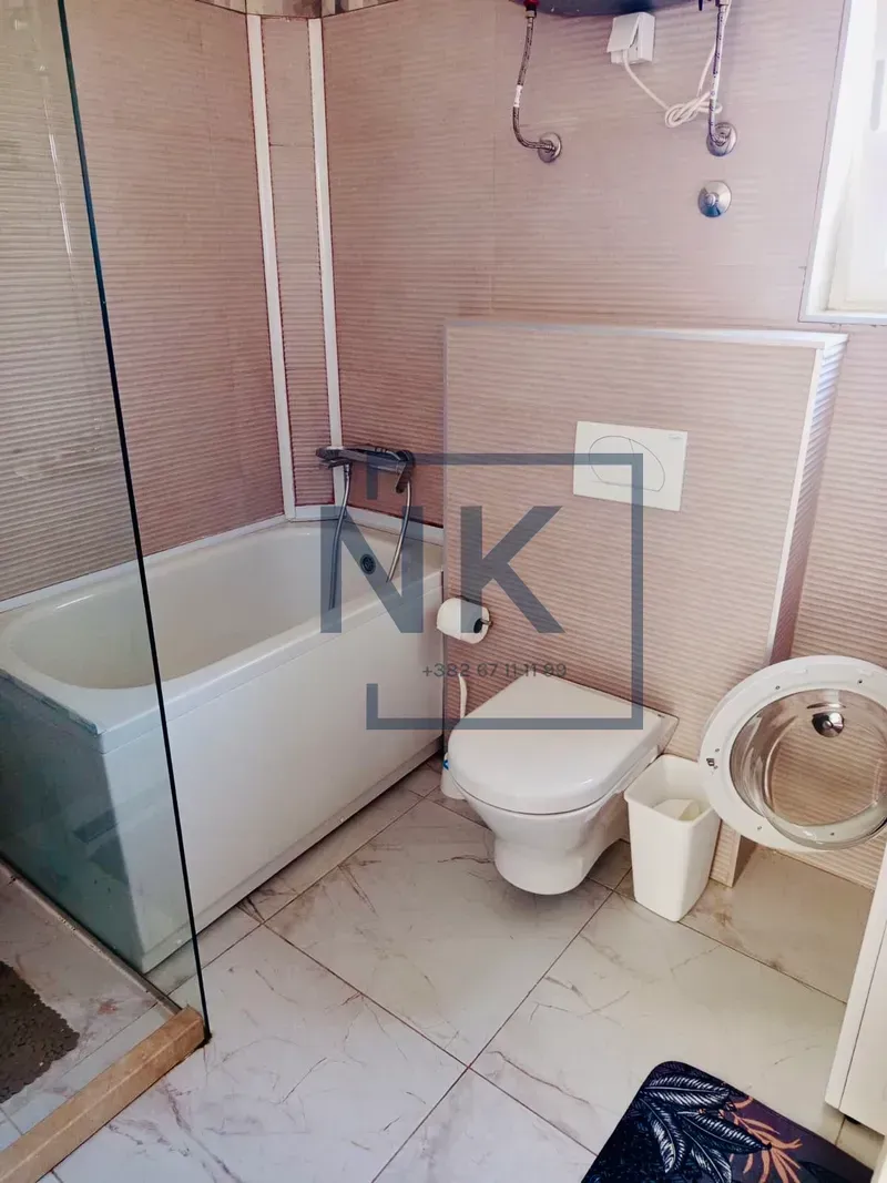 Bathroom equipped with a bathtub, toilet, and glass shower enclosure.