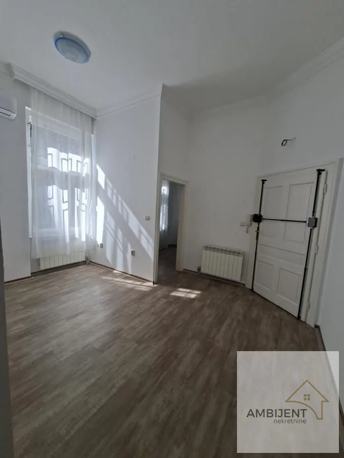 Empty room with laminate flooring, white walls, and a large window.
