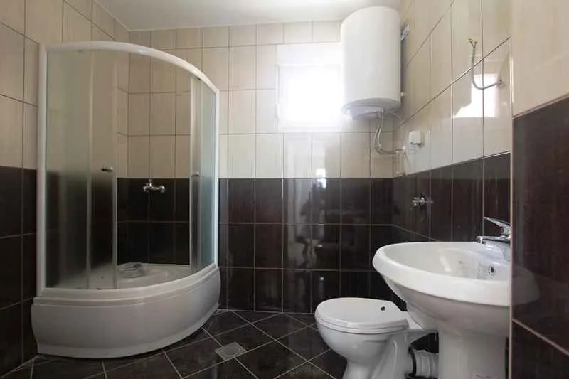 Kupatilo opremljeno tuš kabinom, umivaonikom, wc šoljom i bojlerom.