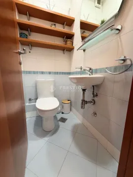 Small bathroom with toilet, washbasin, and wooden wall shelves. - image 14