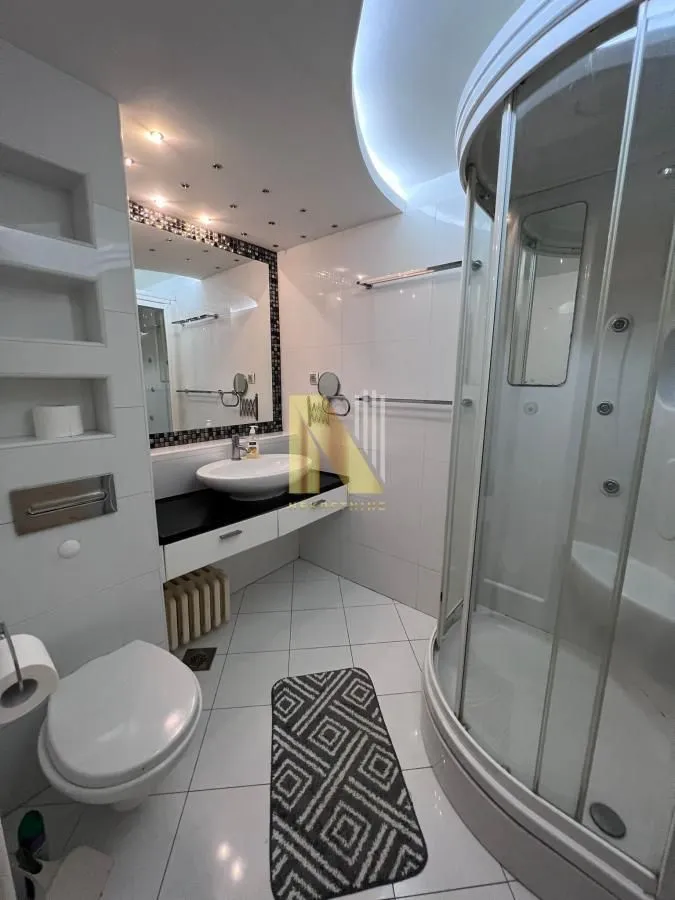 Moderno kupatilo sa tuš kabinom, umivaonikom i WC šoljom.
