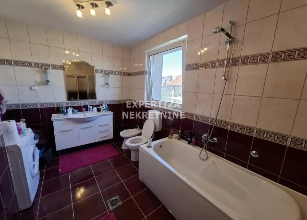 Spacious bathroom with a bathtub, washbasin, and washing machine.
