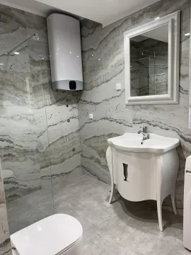 A modern equipped bathroom with a washbasin, shower cabin, and water heater. - image 2