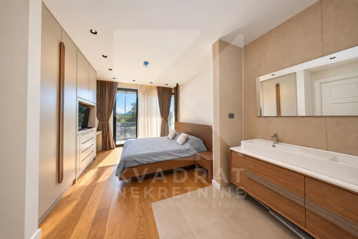Spacious bedroom with a double bed, built-in wardrobe and an open-plan vanity area with a washbasin.