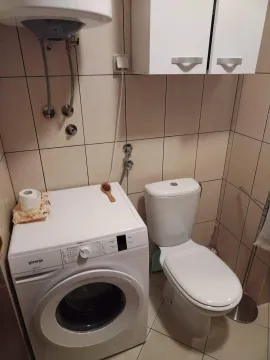 Smaller bathroom with a toilet, washing machine, and water heater. - image 12
