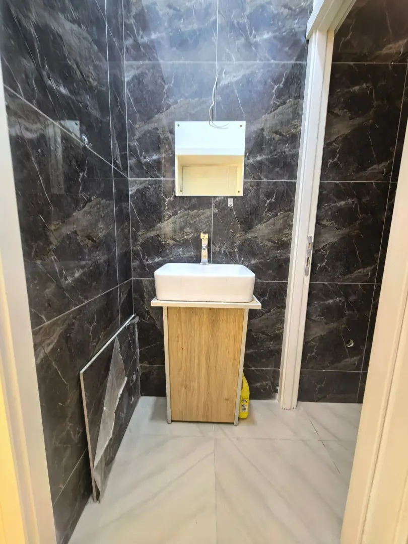 Small bathroom with a washbasin and dark marble tiles.
