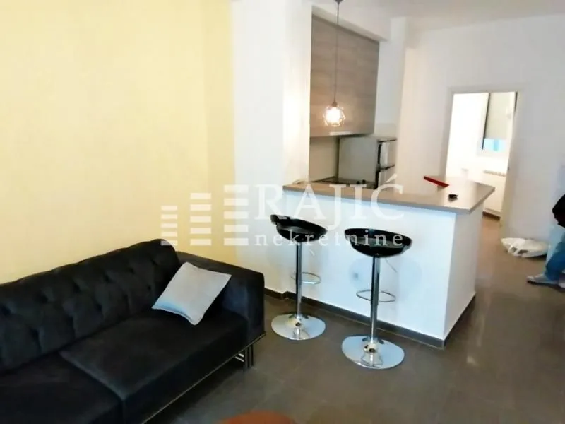 Living room with sofa and a breakfast bar leading to the kitchen.