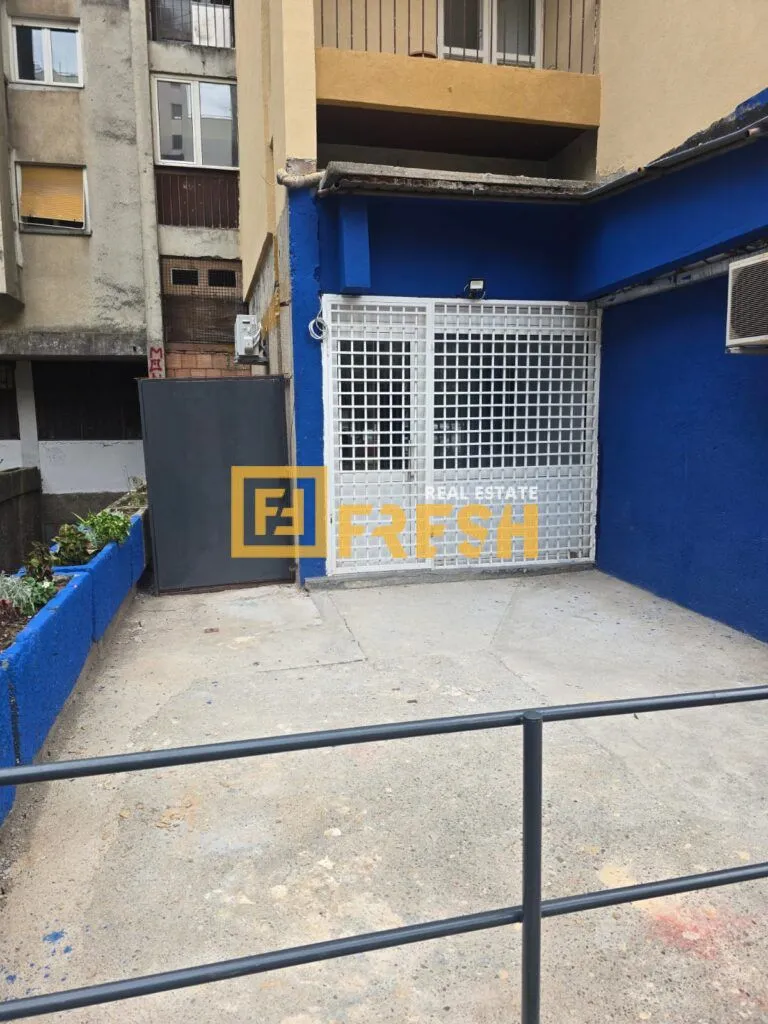 View of the commercial space entrance with a blue facade and security grilles.