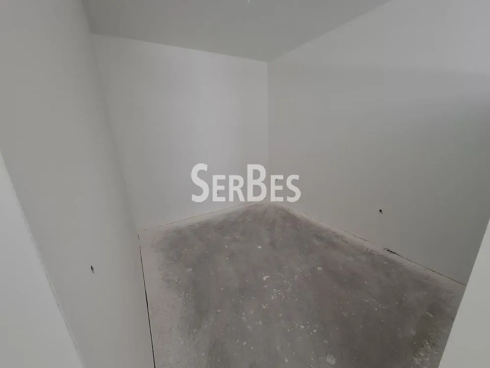 Prazna prostorija sa belim zidovima i sirovim podom u fazi renoviranja.