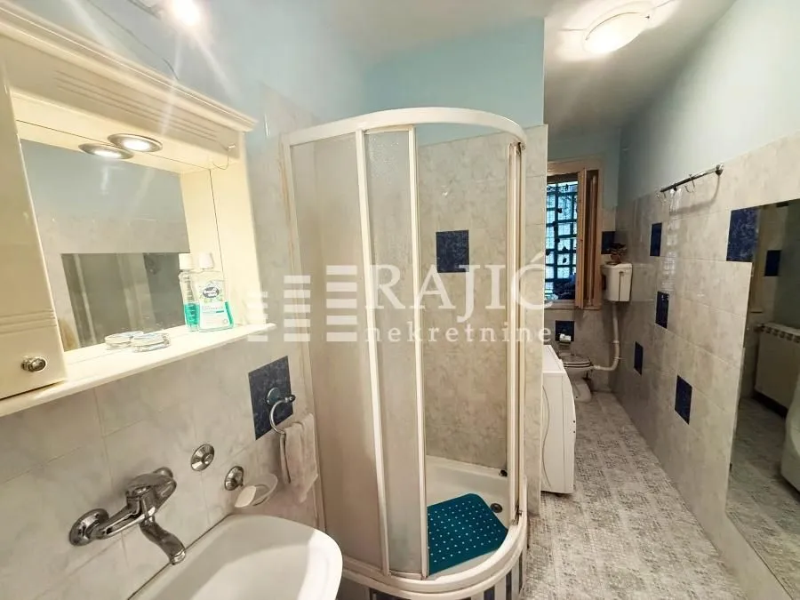 View of the bathroom with a shower cabin, washbasin, and toilet facilities.