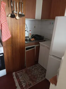 Smaller older kitchen with wooden elements and a refrigerator. - image 4