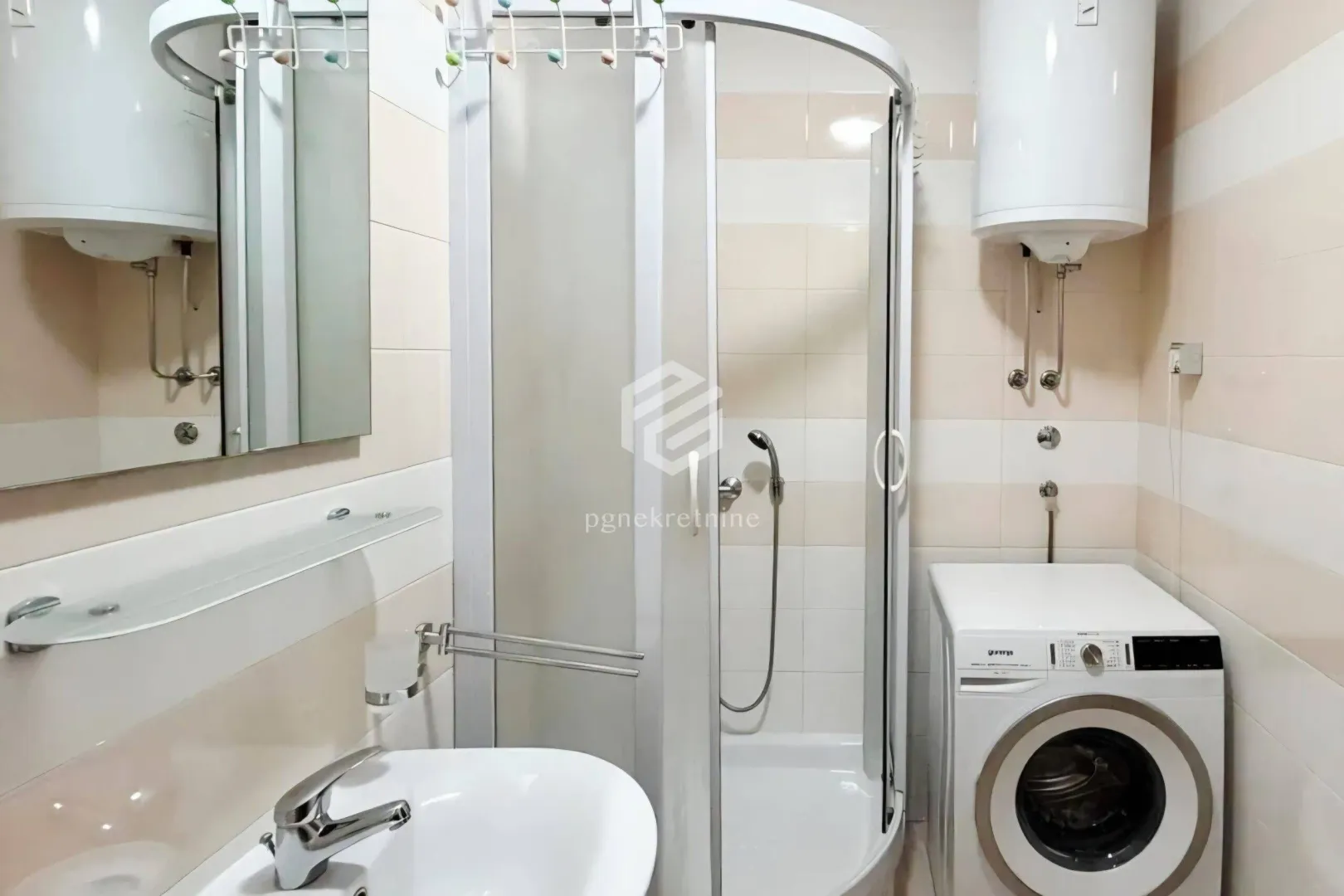 Bathroom with a shower cabin, washbasin, mirror, and washing machine.