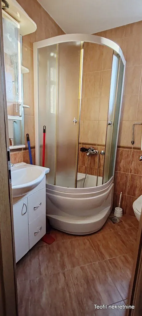 Bathroom equipped with a shower cabin, washbasin, and wall tiles.