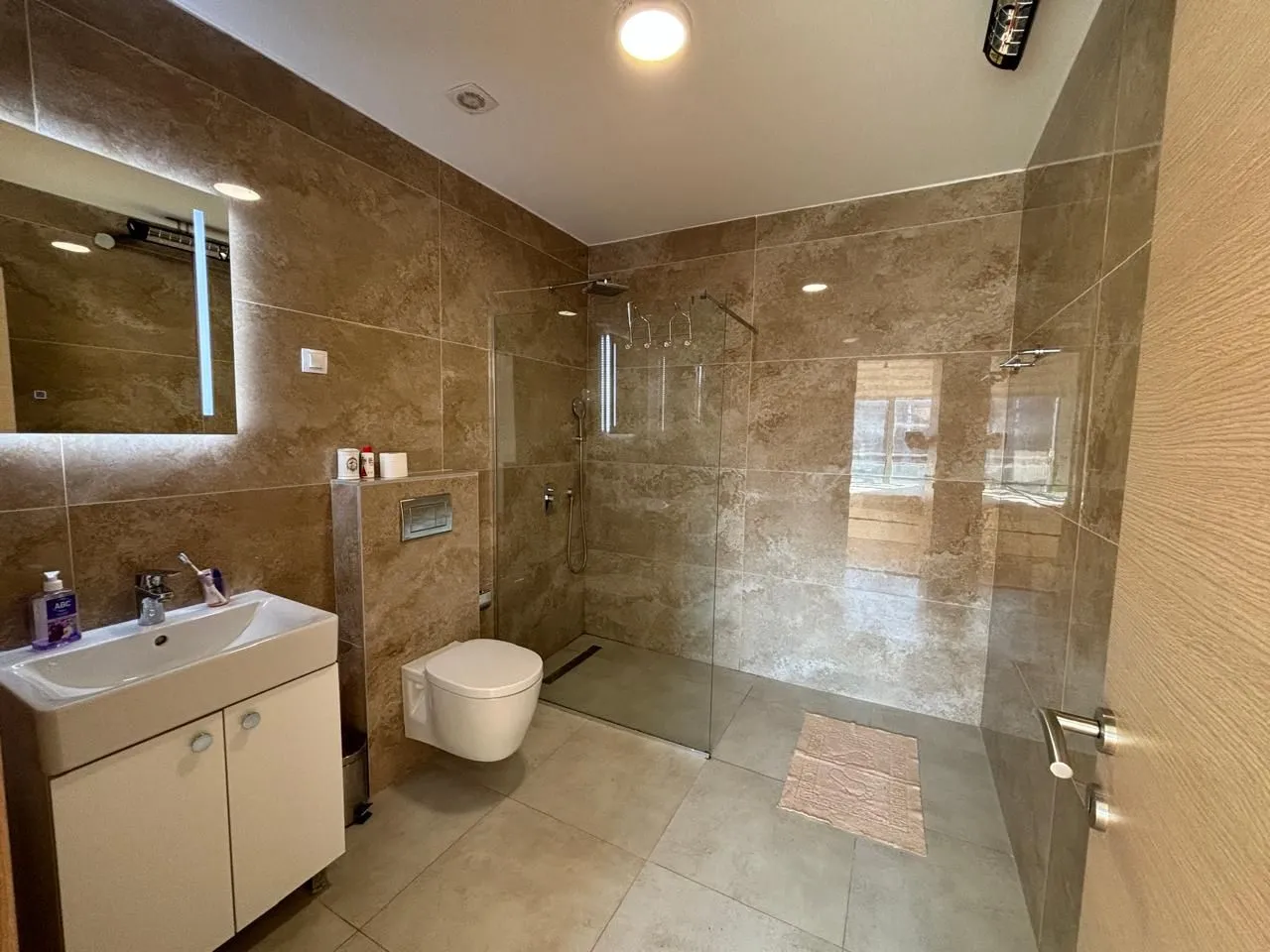 Moderne kupatilo sa tuš kabinom, umivaonikom i WC šoljom.