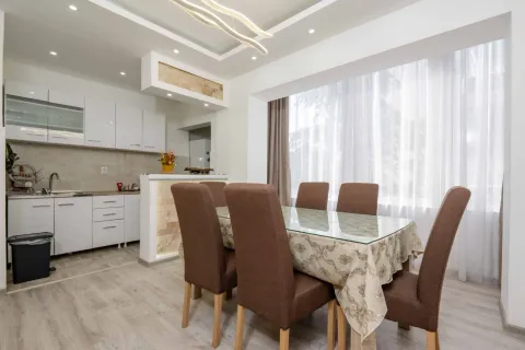 Modern kitchen with a dining area and white cabinets. - image 3