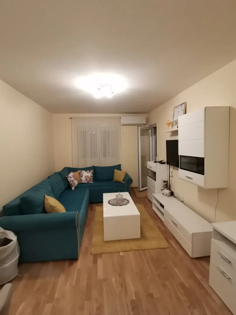 Svijetla dnevna soba sa plavom ugaonom garniturom i bijelim klupskim stolom.