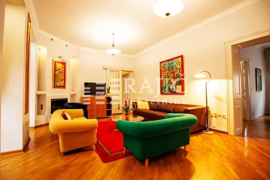 Spacious living room with seating furniture and parquet flooring.