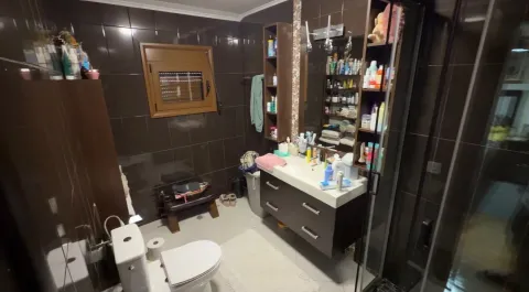 Manje uredno kupatilo sa tamnim pločicama, umivaonikom i wc šoljom. - image 8