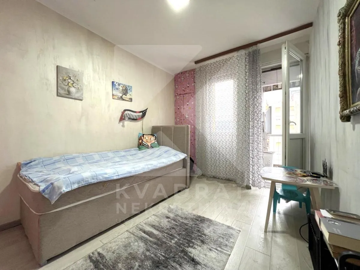 Smaller bedroom with a bed, small table and access to the terrace.