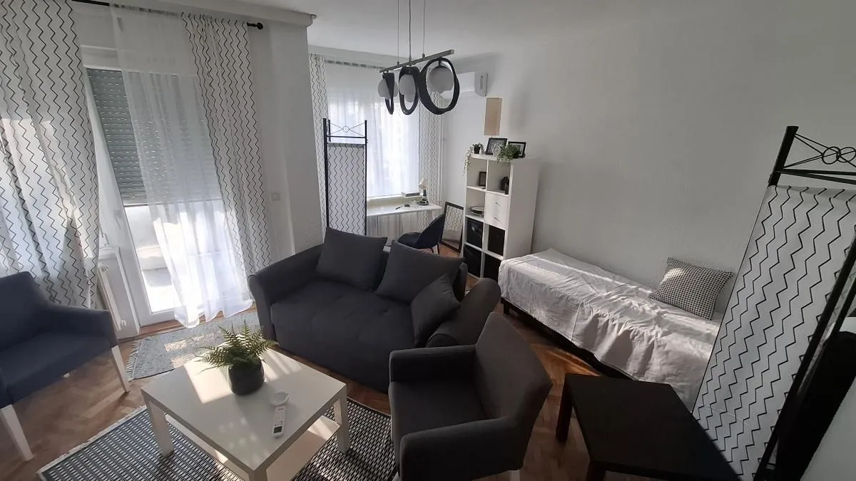 Dnevna soba sa garniturom za sedenje, foteljama i belim klub stočićem.