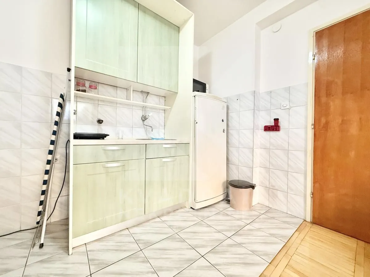 Small kitchen with light-colored cabinetry, a refrigerator, and tiled flooring.