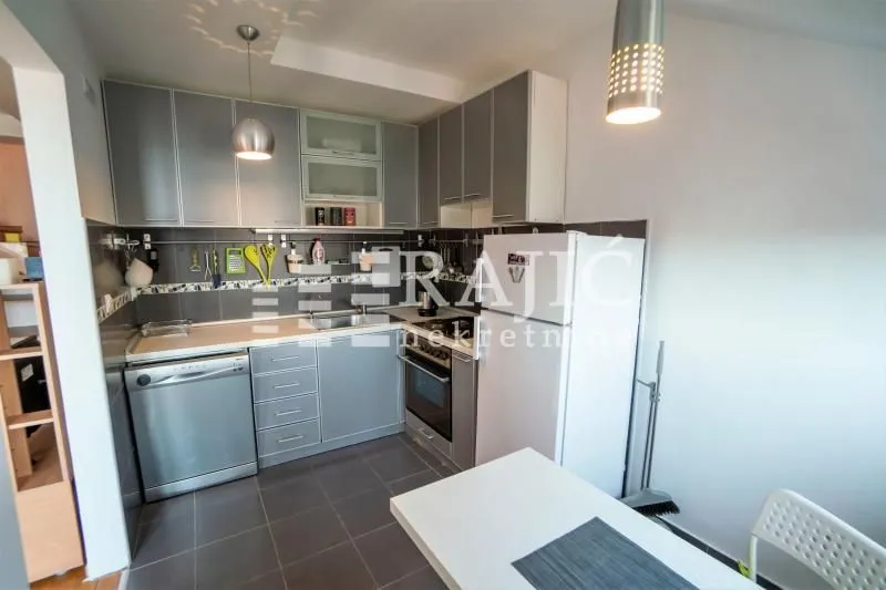 Small kitchen with grey cabinets, built-in appliances and a dining table.