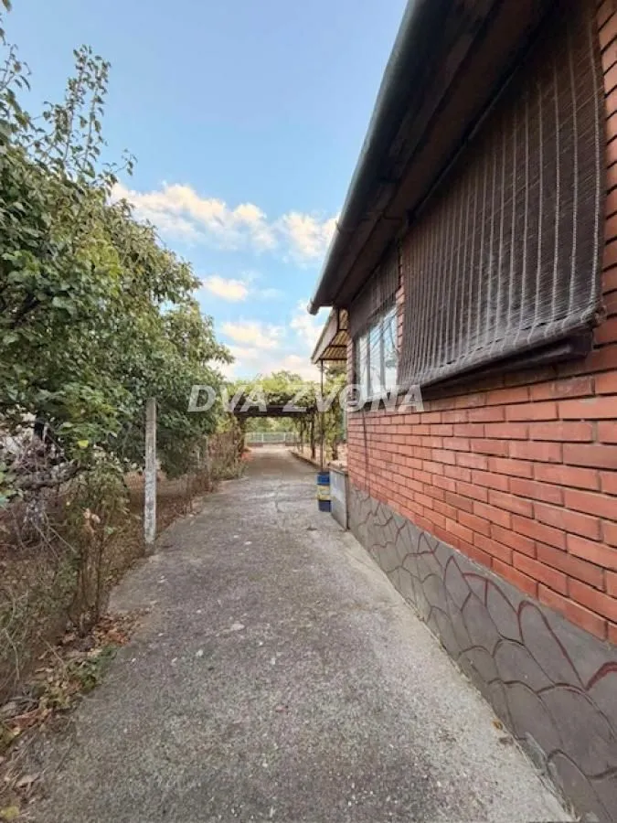 Dvorište kuće sa stazom i zelenilom pored zgrade.