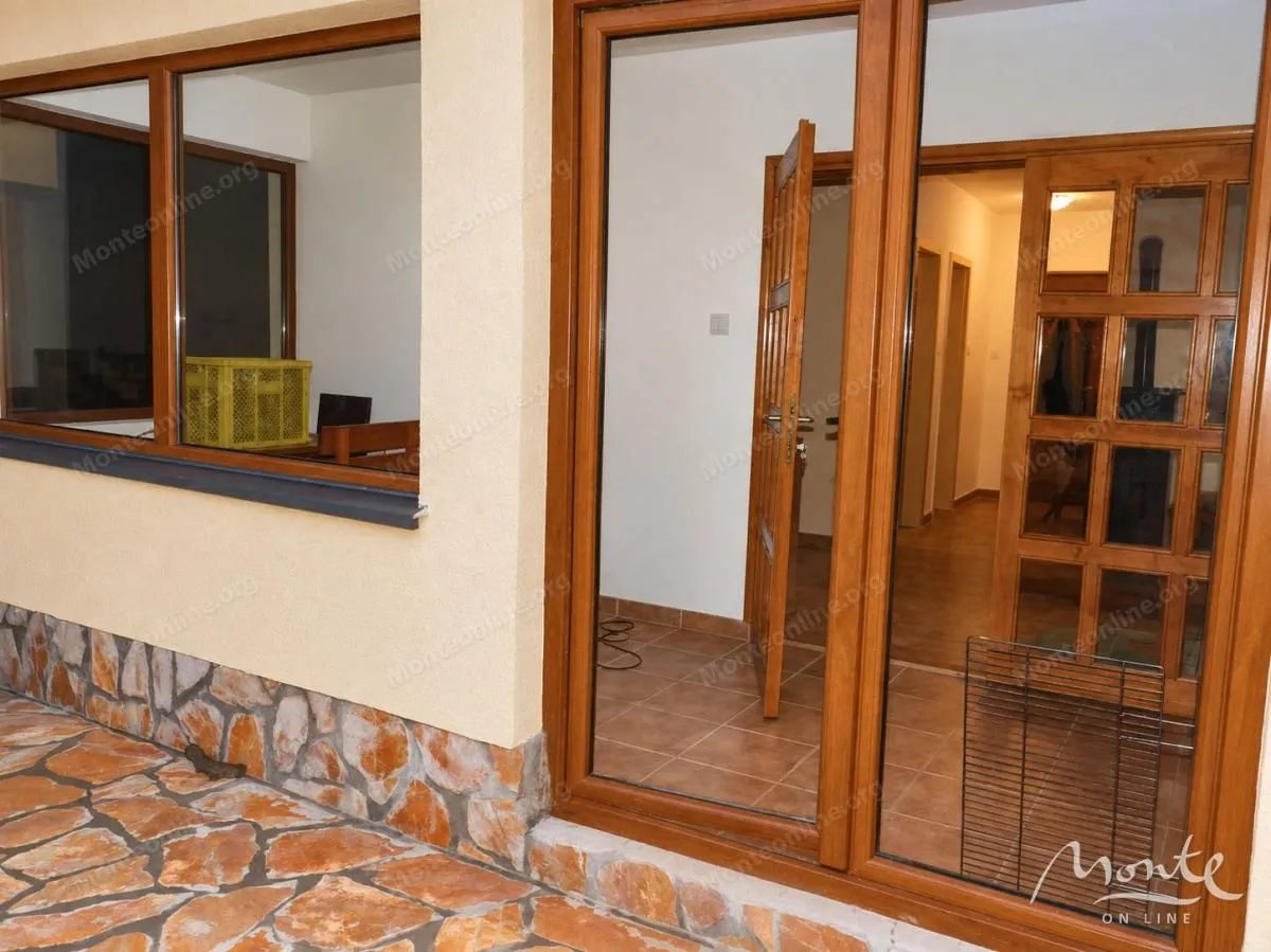 View of the entrance door and window of the house with a paved courtyard.