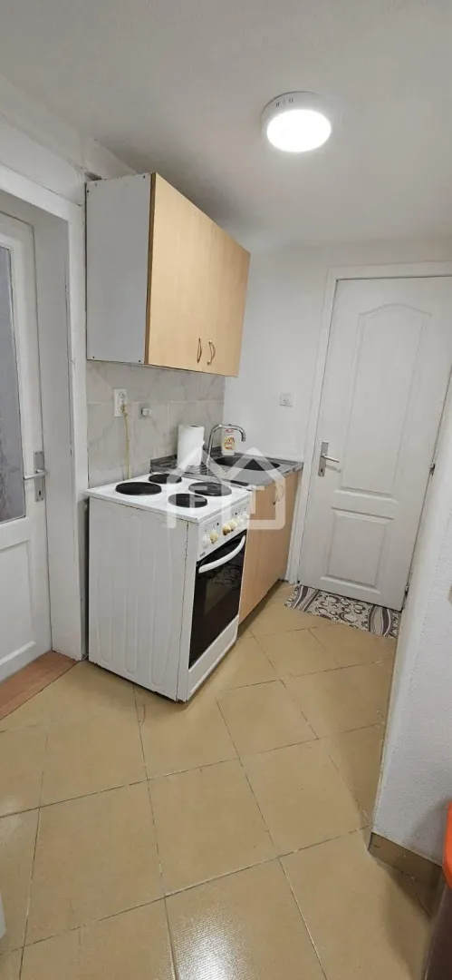 Small kitchen with a stove, sink, and upper kitchen cabinets.