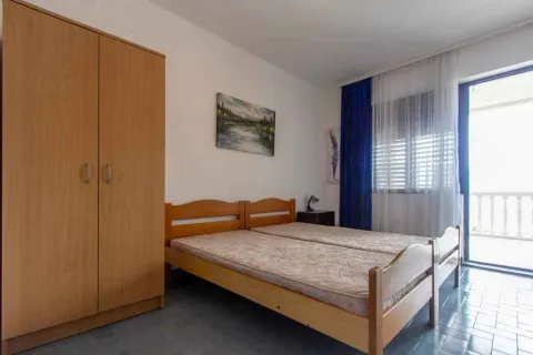 Namještena spavaća soba sa drvenim krevetom, ormarom i izlazom na terasu. - image 8