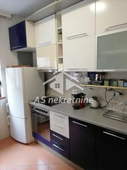 Small kitchen with white and dark cabinets and a refrigerator.