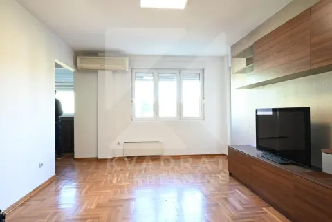 Living room with wooden parquet flooring, TV unit, and air conditioning. - image 2