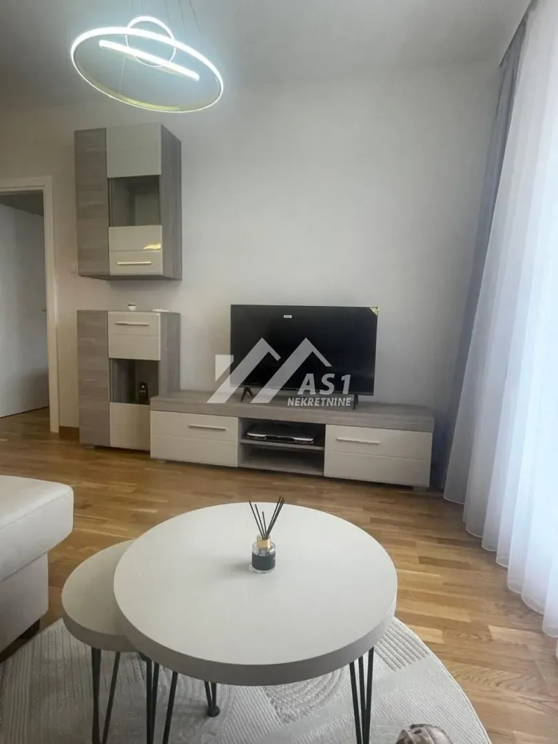 Pogled na deo dnevnog boravka sa TV komodom i stočićem.