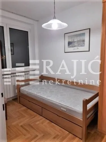 Small bedroom with a wooden bed and parquet flooring.