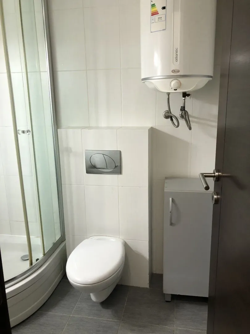 Bathroom with a shower cabin, toilet, and water heater.