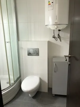 Bathroom with a shower cabin, toilet, and water heater. - image 27