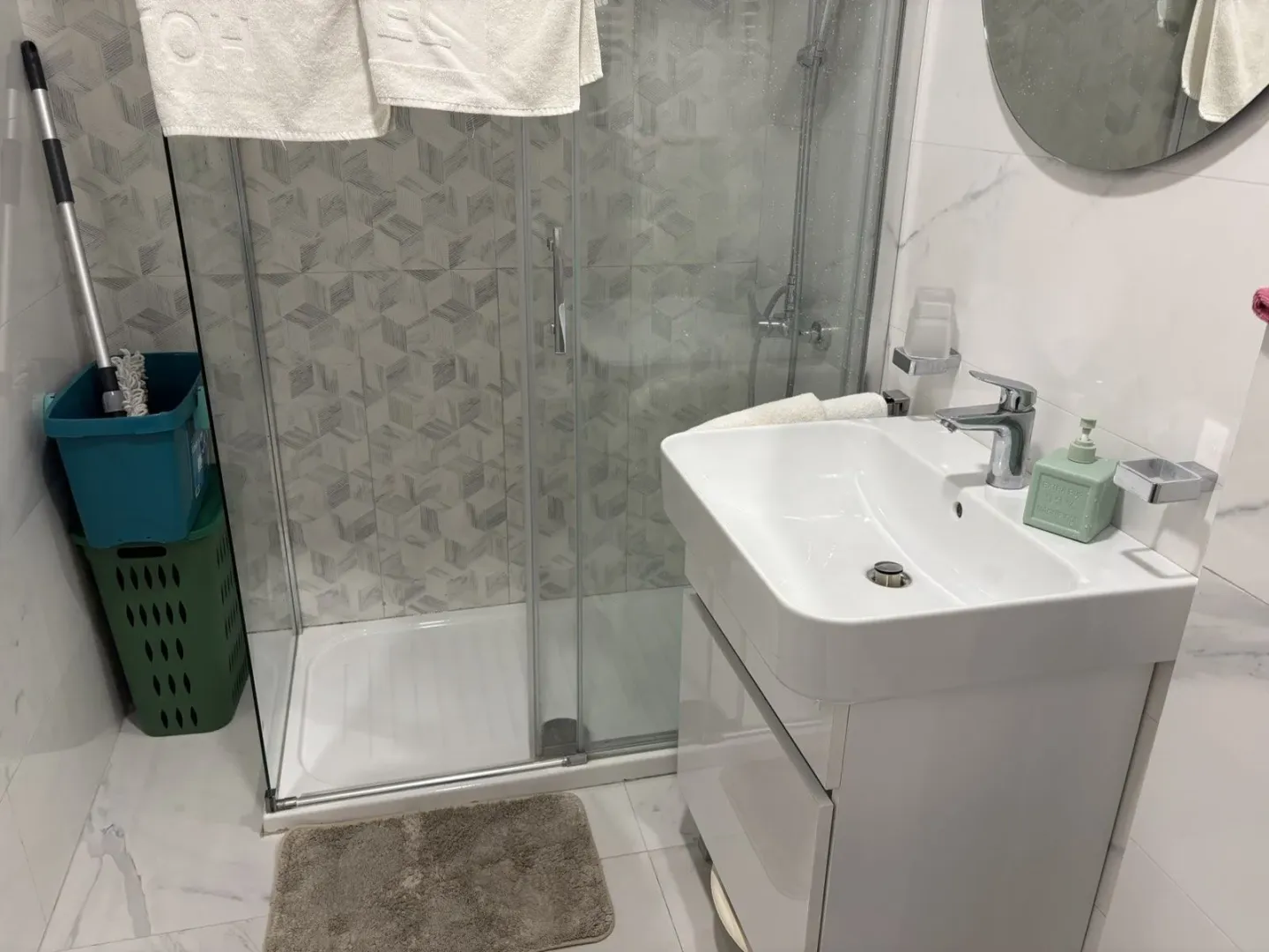 Svijetlo kupatilo sa tuš kabinom i modernim lavaboom sa ormarićem.