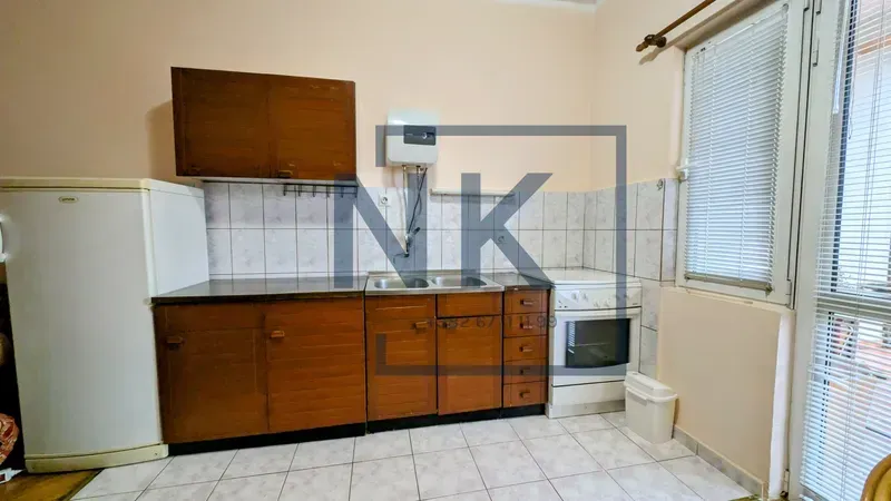 Small kitchen with wooden cabinets, refrigerator, stove, and access to the terrace.