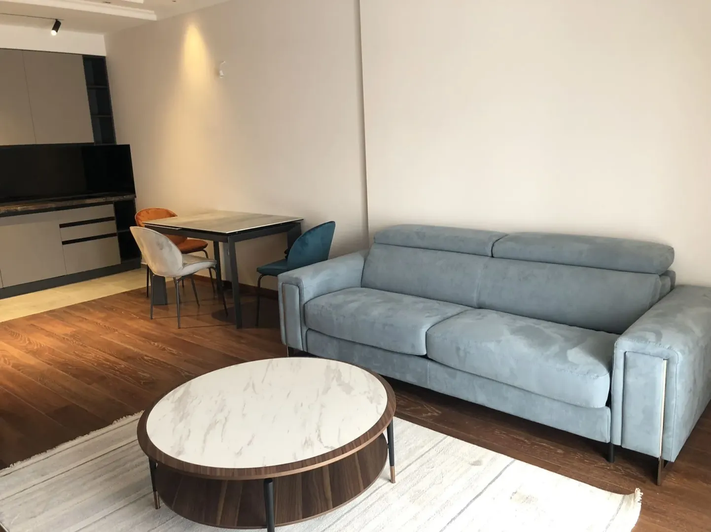 Bright living room with a blue sofa, coffee table, and dining set.