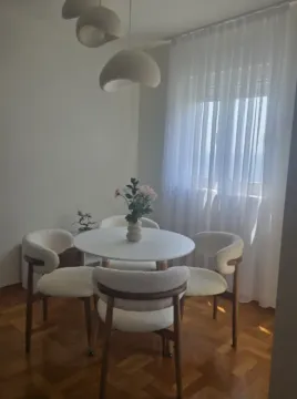 Trpezarija sa okruglim stolom i modernim stolicama pored prozora. - image 9