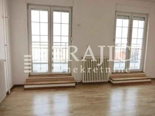 Empty room with parquet flooring and double balcony doors.