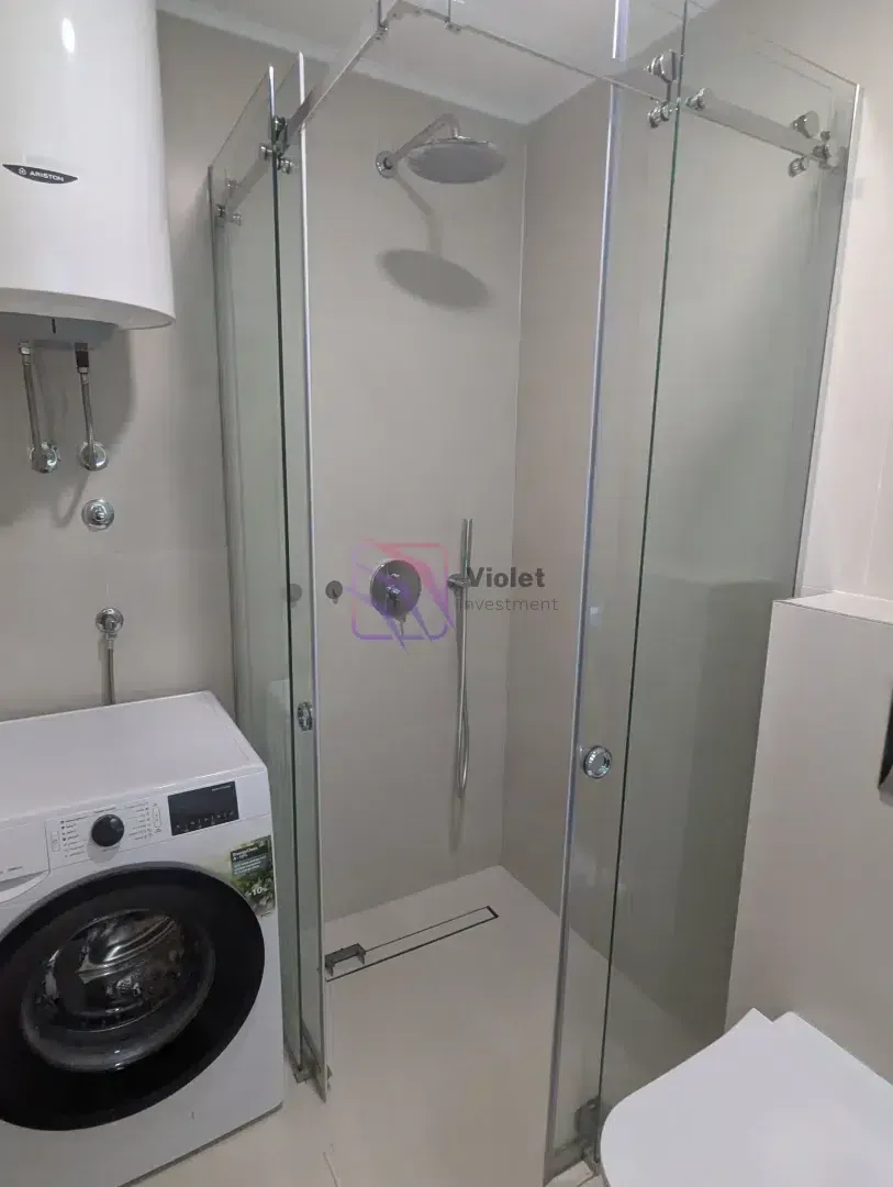 Bathroom with a shower cabin, water heater, and washing machine.