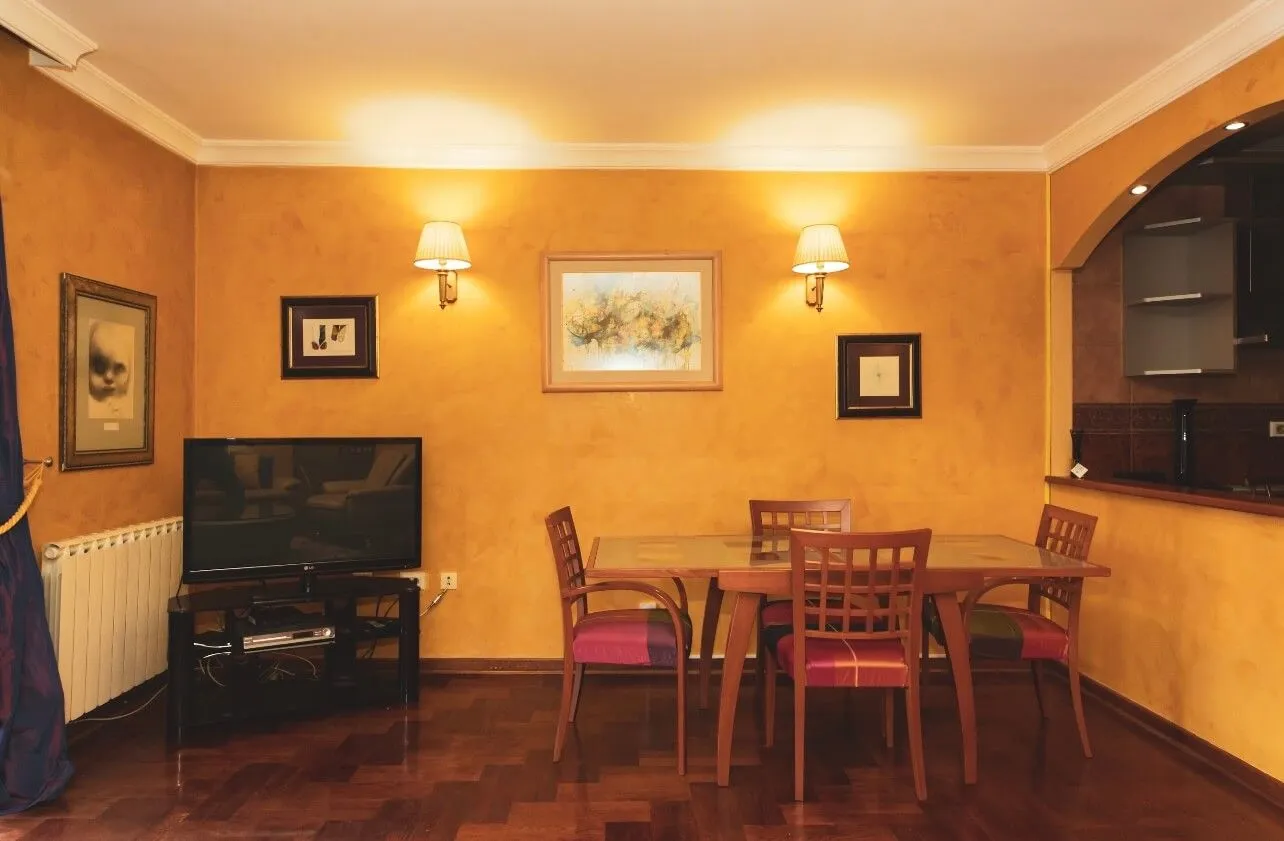 Living room with a dining area, a wooden table, and a television.