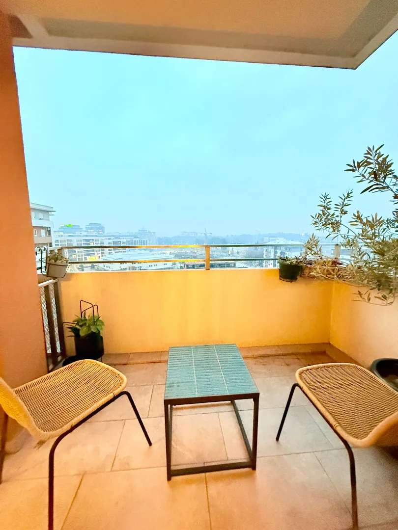 Furnished balcony with seating set and city view.