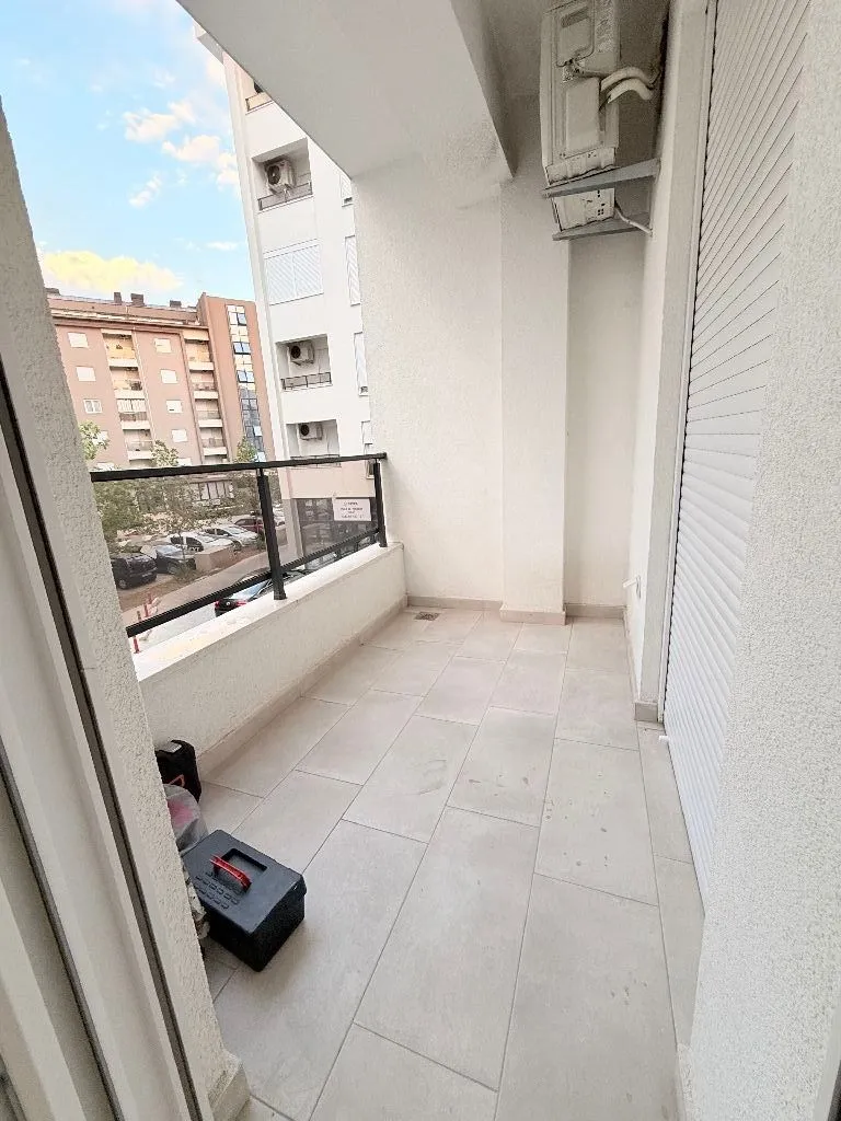 Uski popločani balkon sa pogledom na susjedne zgrade.
