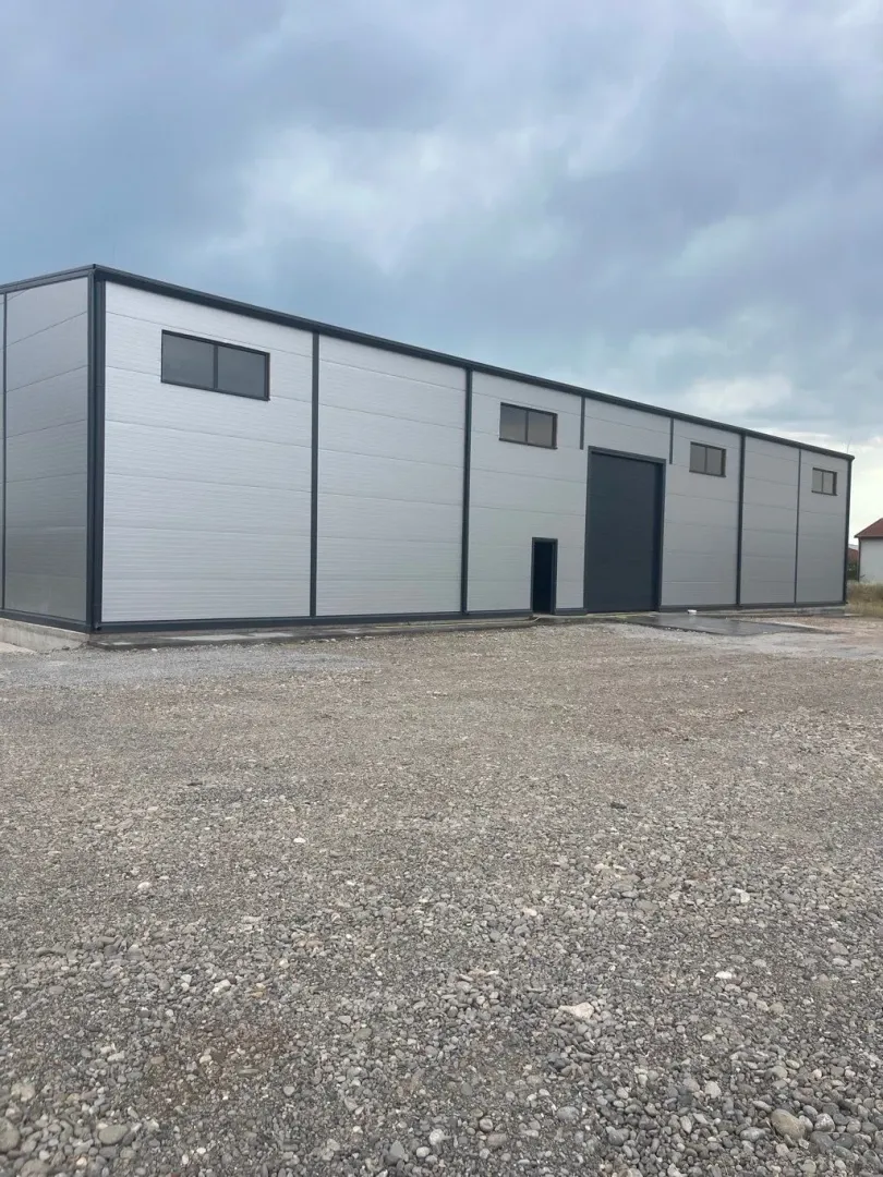 Exterior of a modern industrial warehouse with a gravel yard.