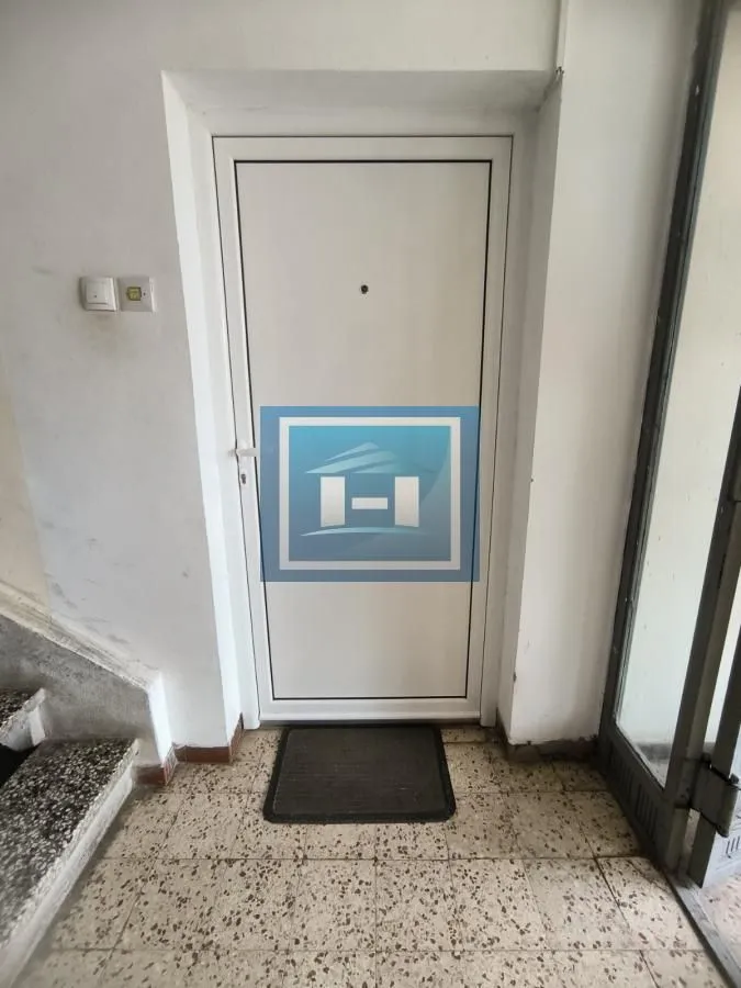 Ulazna vrata u zgradu sa popločanim podom i stepeništem.