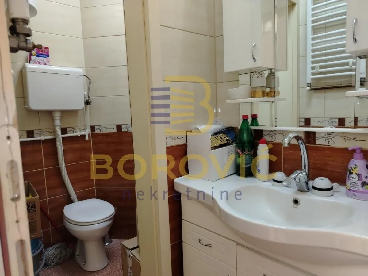 Smaller bathroom with a washbasin, toilet bowl, and wall tiles in brown and beige tones.