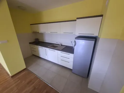 Kuhinja opremljena belim elementima i frižiderom. - image 4